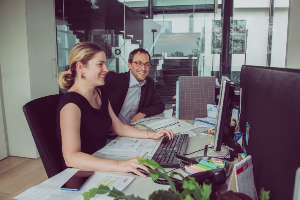 photo of man and woman looking at computer