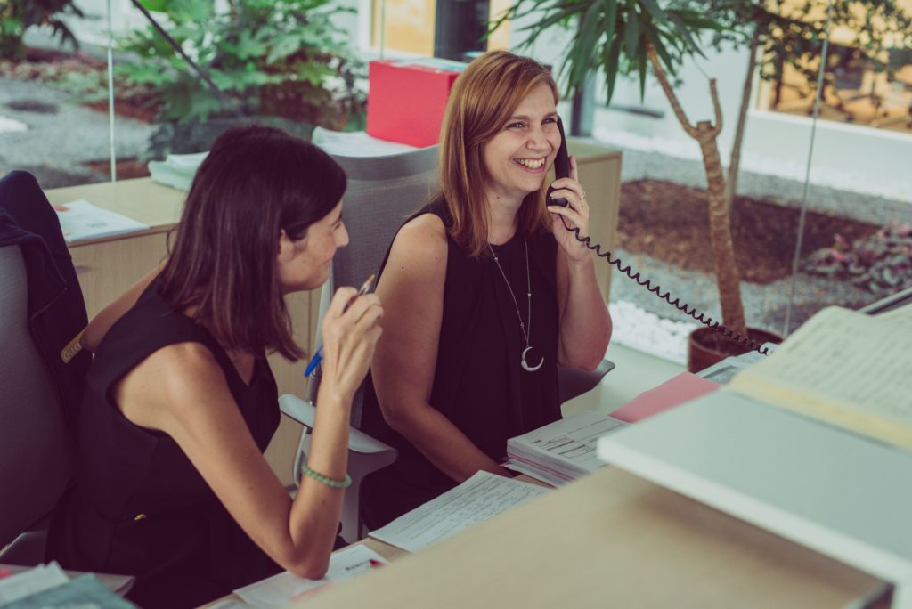 photo of two women at a desk, one is on the phone