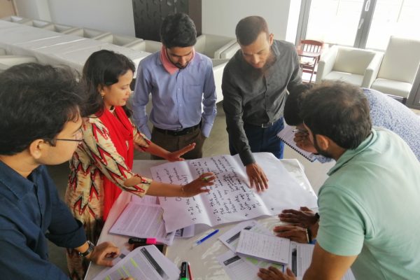 photo of people gathered around documents on a table