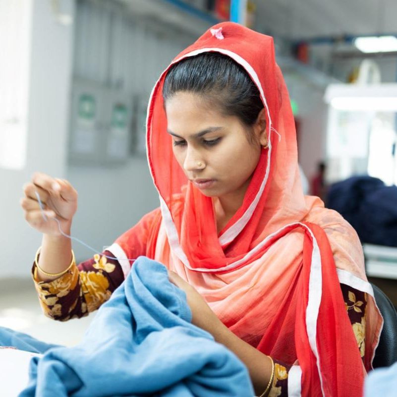 photo of woman hand-sewing in a factory setting
