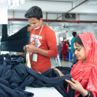 Man and woman measuring cloth for the production of clothing at an apparel factory.