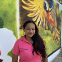 Photo of woman in a pink top standing in front of a mural