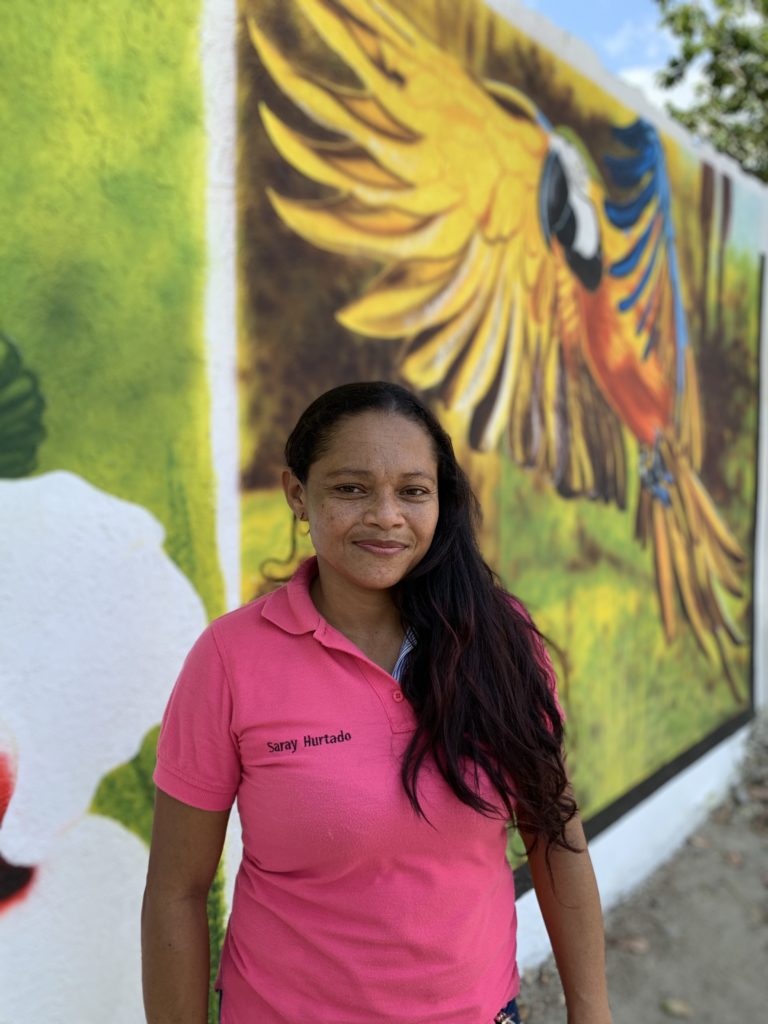 Photo of woman in a pink top standing in front of a mural