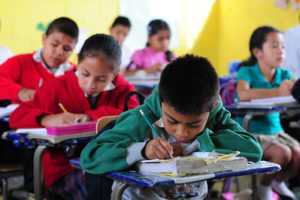 Children writing in schoolbooks, photo by Maria Fleischmann, World Bank
