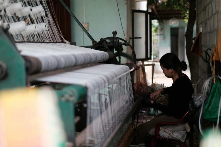 A woman sits at a loom.