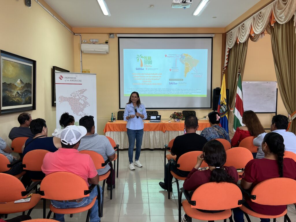 Yolanda stands in front of a group of people, speaking into a microphone