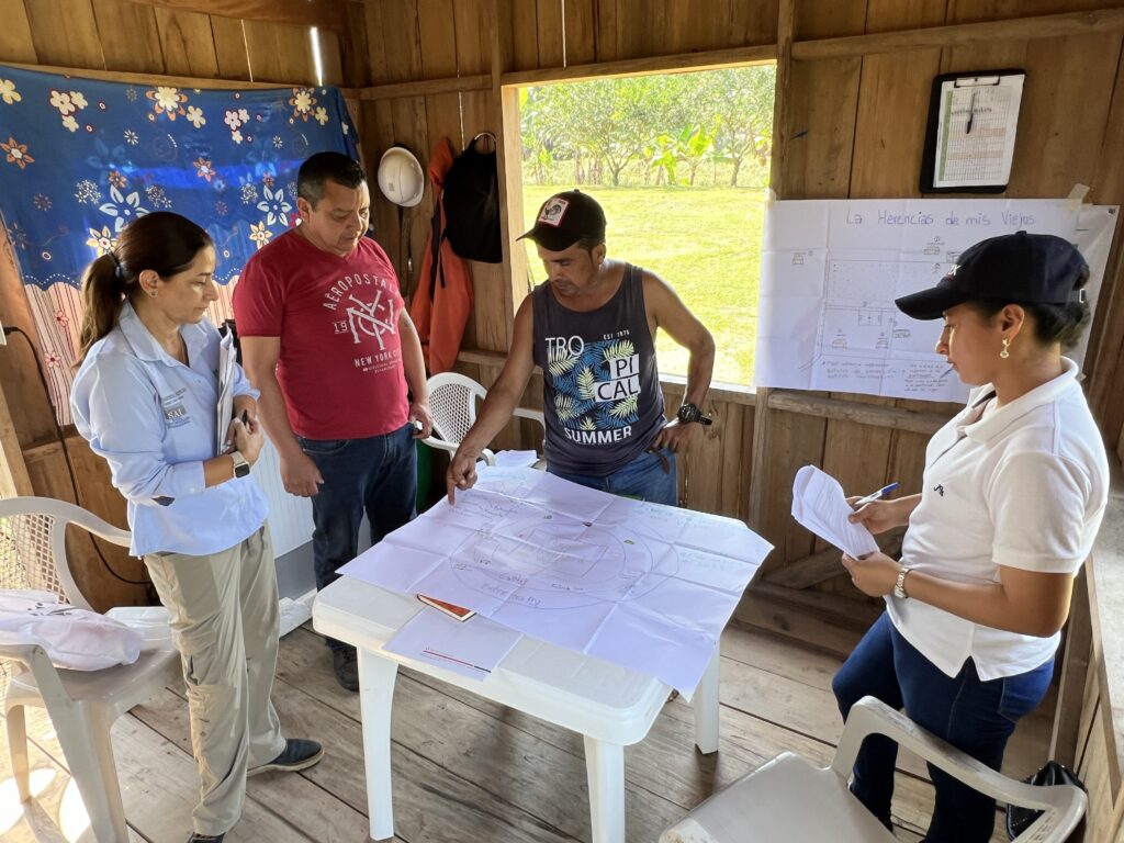 Yoilanda stands around a table with three people, looking at paper on the table