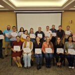 Group of people pose for photo holding certificates