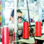 a person sits behind spindles of thread